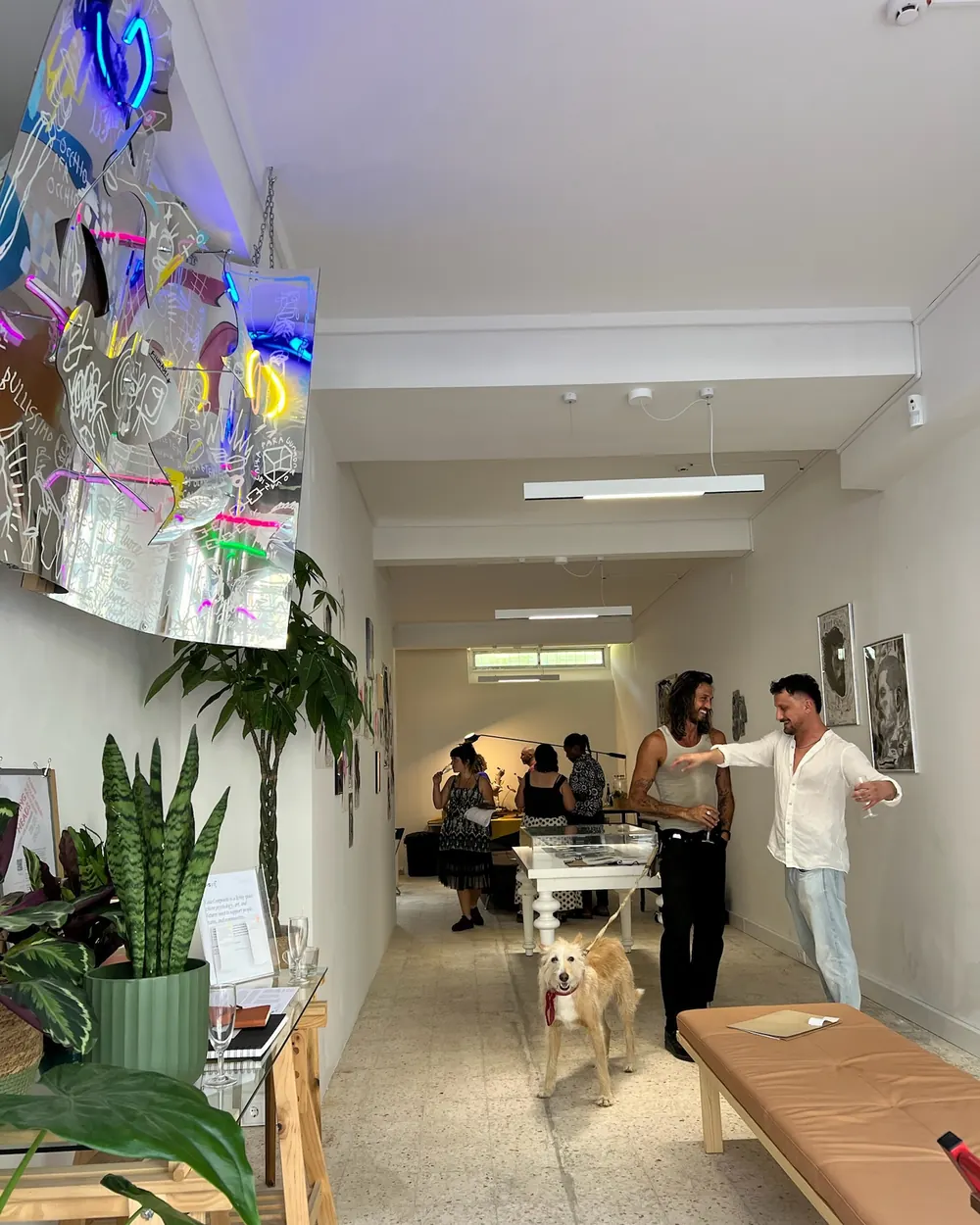 Inauguração: visitantes na galeria, com uma escultura de néon suspensa